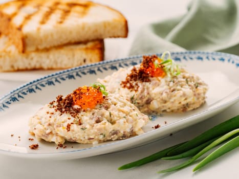 Fish appetizer forshmak - minced meat from herring fish, decorated caviar on plate. Traditional Jewish cuisine dish vorschmack forshmak made of herring fillet as independent dish on wooden background