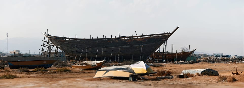 Construction of a wooden ship. Shipyard of traditional Dhow wooden boat on Iranian Qeshm Island. Tradition Lenj Fishing Boat in Qeshm Island in Southern Iran. Old wooden stealth smuggler's ship.