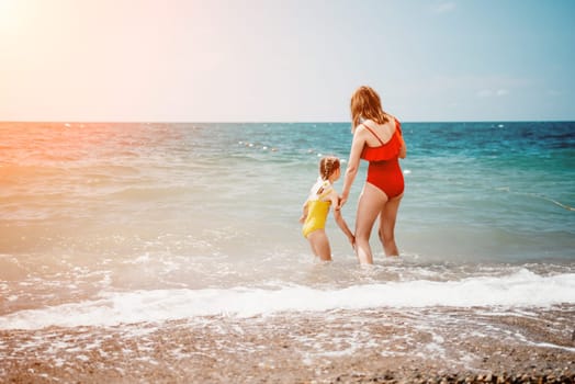 Happy loving family mother and daughter having fun together on the beach. Mum playing with her kid in holiday vacation next to the ocean - Family lifestyle and love concept.