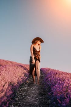 Close up portrait of young beautiful woman in a white dress and a hat is walking in the lavender field and smelling lavender bouquet.