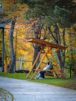 Cute couple enjoying bright autumn colors while relaxing on park bench.