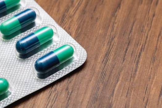 Blue pills in pack close up on wooden table, copy space