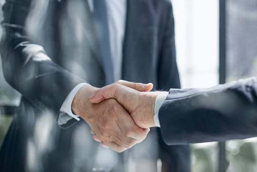 Two business people shaking hands in front of their colleagues