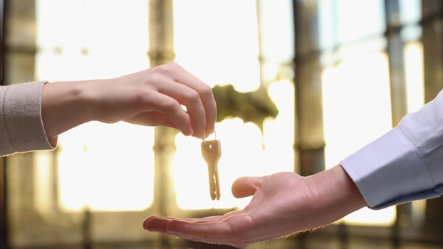 From hand to hand. Close up shot of hand of female seller owner of house apartment office holding keys giving it to young woman buyer renter after conclusion of successful deal and getting downpayment