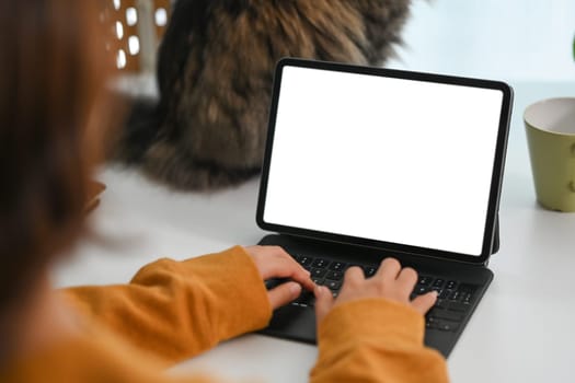 View over shoulder young female freelancer working on digital tablet at home.