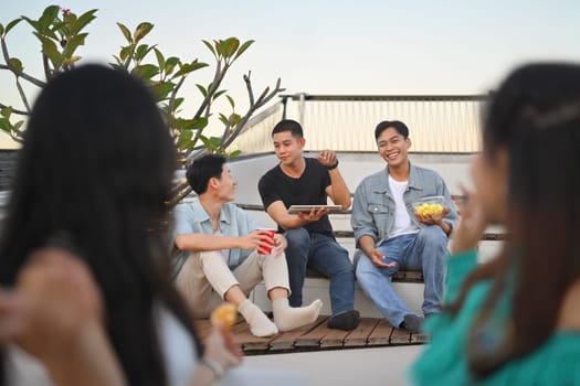 Group of happy friends talking and sharing nice moments together at the rooftop party.