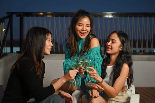 Happy female friends having fun drinking wine on rooftop dinner party. Friendship lifestyle concept.