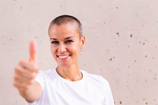 young woman with short hair smiling happy with with thumb up looking at camera, copy space for text