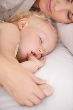 Mother, baby and kid suck thumb in home, adorable and cute innocent child with parent in house. Young blonde toddler, finger and mouth of healthy little girl sleeping in bedroom together with mama.