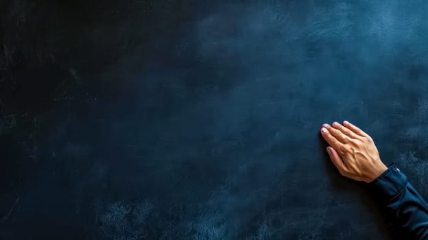 A single hand resting on a dark, textured blackboard surface, conveying themes of contemplation, education, and expression, banner with copy space