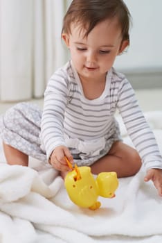 Baby, playing and toys in living room floor, duck and sensory growth in family home. Curious, girl and play for child development, games and childhood memories or fun to learn, cognition or kids.