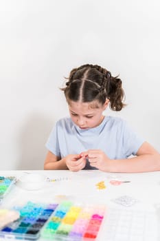 Little girl enjoys crafting colorful bracelets with vibrant clay beads set.