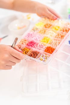Little girl enjoys crafting colorful bracelets with vibrant clay beads set.