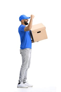 A male deliveryman, on a white background, full-length, with a box, raised his hand up.