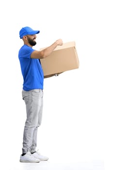 A male deliveryman, on a white background, in full height, points to the box.