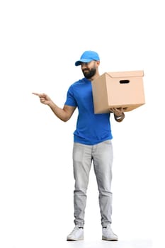 A male deliveryman, on a white background, full-length, with a box, points to the side.