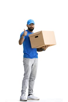 A male deliveryman, on a white background, in full height, with a box, shows a thumbs up.