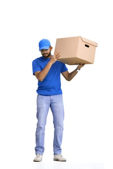 A male deliveryman, on a white background, in full height, shakes a box.