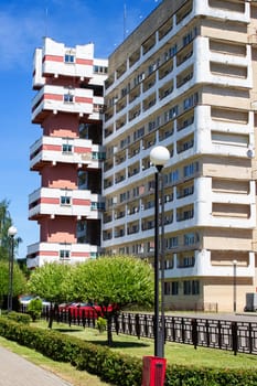 Tall residential building and alley with green trees, city landscape