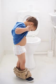 Boy child, potty training and toilet with thinking, diaper and pants on floor for learning, development and progress. Kid, family home and bathroom with ideas, problem solving or solution in nappy.