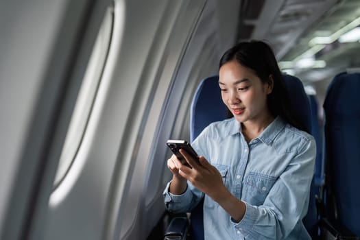 Asian people female person onboard, airplane window, using mobile while on the plane.