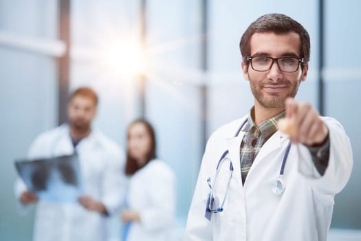 Young doctor man pointing with finger to the camera and to you, hand sign, positive and confident gesture from the front