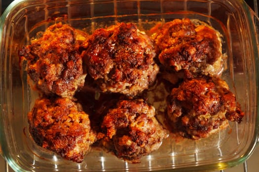 Meatballs with a succulent and crispy exterior rest in a glass baking dish, embodying the warmth of a home-cooked meal.