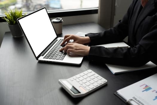 Mockup laptop, blank screen. Woman accountant using calculator and laptop in office.