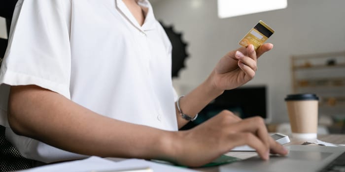 Young woman makes a purchase on the Internet on the laptop with credit card.