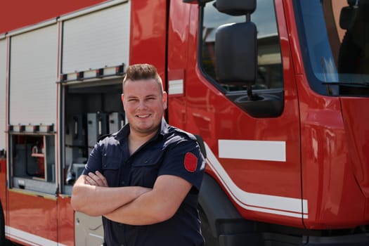 Confident firefighter stands with crossed arms, exuding resilience and preparedness, ready to respond to emergencies alongside a modern fire truck, showcasing the heroism and strength of the fire service.