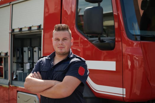 Confident firefighter stands with crossed arms, exuding resilience and preparedness, ready to respond to emergencies alongside a modern fire truck, showcasing the heroism and strength of the fire service.