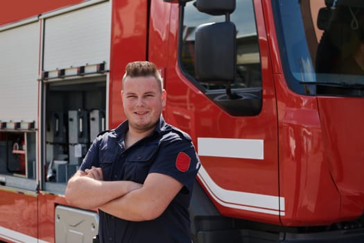 Confident firefighter stands with crossed arms, exuding resilience and preparedness, ready to respond to emergencies alongside a modern fire truck, showcasing the heroism and strength of the fire service.