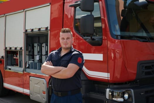 Confident firefighter stands with crossed arms, exuding resilience and preparedness, ready to respond to emergencies alongside a modern fire truck, showcasing the heroism and strength of the fire service.