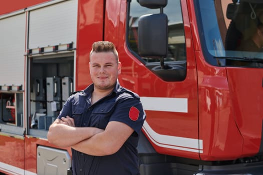 Confident firefighter stands with crossed arms, exuding resilience and preparedness, ready to respond to emergencies alongside a modern fire truck, showcasing the heroism and strength of the fire service.