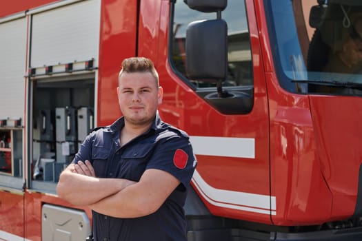 Confident firefighter stands with crossed arms, exuding resilience and preparedness, ready to respond to emergencies alongside a modern fire truck, showcasing the heroism and strength of the fire service.