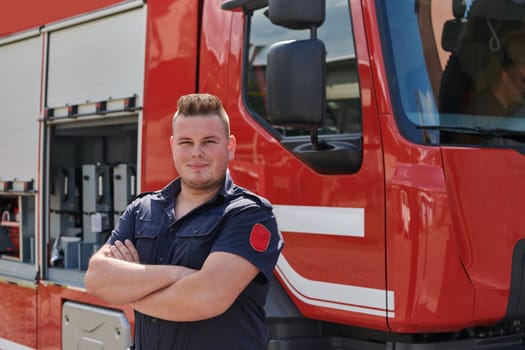 Confident firefighter stands with crossed arms, exuding resilience and preparedness, ready to respond to emergencies alongside a modern fire truck, showcasing the heroism and strength of the fire service.