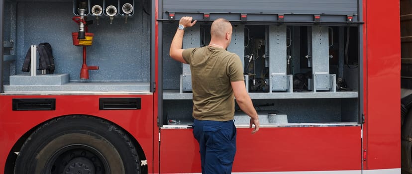 A dedicated firefighter preparing a modern firetruck for deployment to hazardous fire-stricken areas, demonstrating readiness and commitment to emergency response.