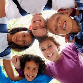 Children, woman and huddle in happy portrait, trees and sunshine with outdoor on playground. Students, teacher or diversity on school field, summer or solidarity with education support in urban town.