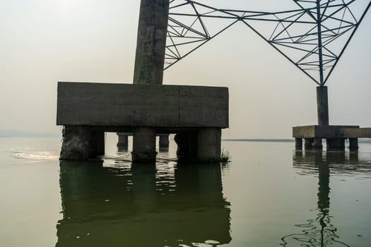 Reinforced concrete power line support across the river, located in the water