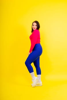 Woman with curvy figure in fashionable sportswear on a grey and yellow background.