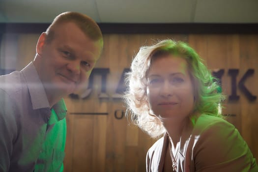 Adult man and woman are conversing on stage in dimly lit room before a performance or interview. The actors, actress, host, journalist, and paparazzi capturing their intimate, secretive conversation