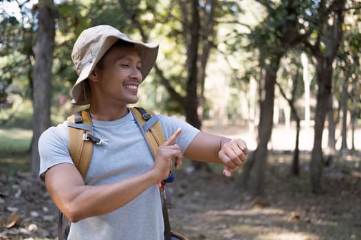 Young male backpacker looking at smart watch in the forest.
