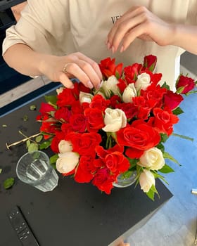 Female hands make a bouquet of red and white small roses. High quality photo