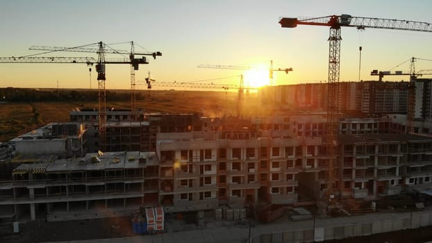 Silhouettes of construction cranes at sunset. Drone video