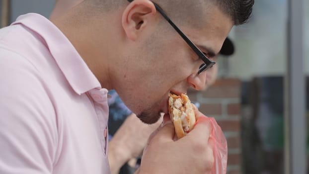 A man from Jordan eats a sandwich on the street