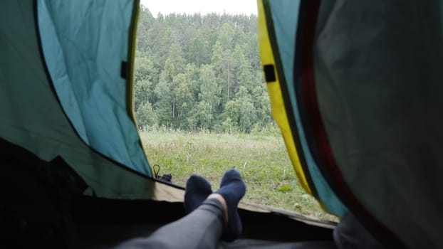 Legs of a man resting in a tent against the background of the forest