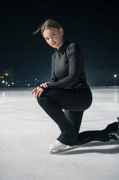 Beautiful young woman ice skating and performing short program over city outdoor ice arena. Winter activities concept