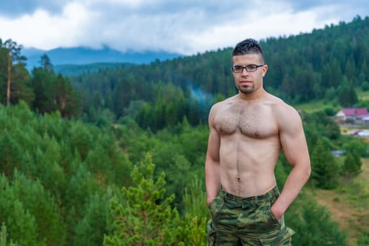 Handsome athletic Arab guy without a T-shirt on the background of the beautiful nature of the South Urals