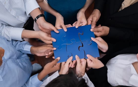 Diverse corporate officer workers collaborate in office, connecting puzzle pieces to represent partnership and teamwork. Unity and synergy in business concept by merging jigsaw puzzle. Concord