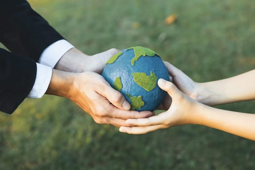 Businessman hand giving Earth globe to little boy as Earth day concept as corporate social responsible to contribute greener environmental protection for sustainable future generation. Gyre